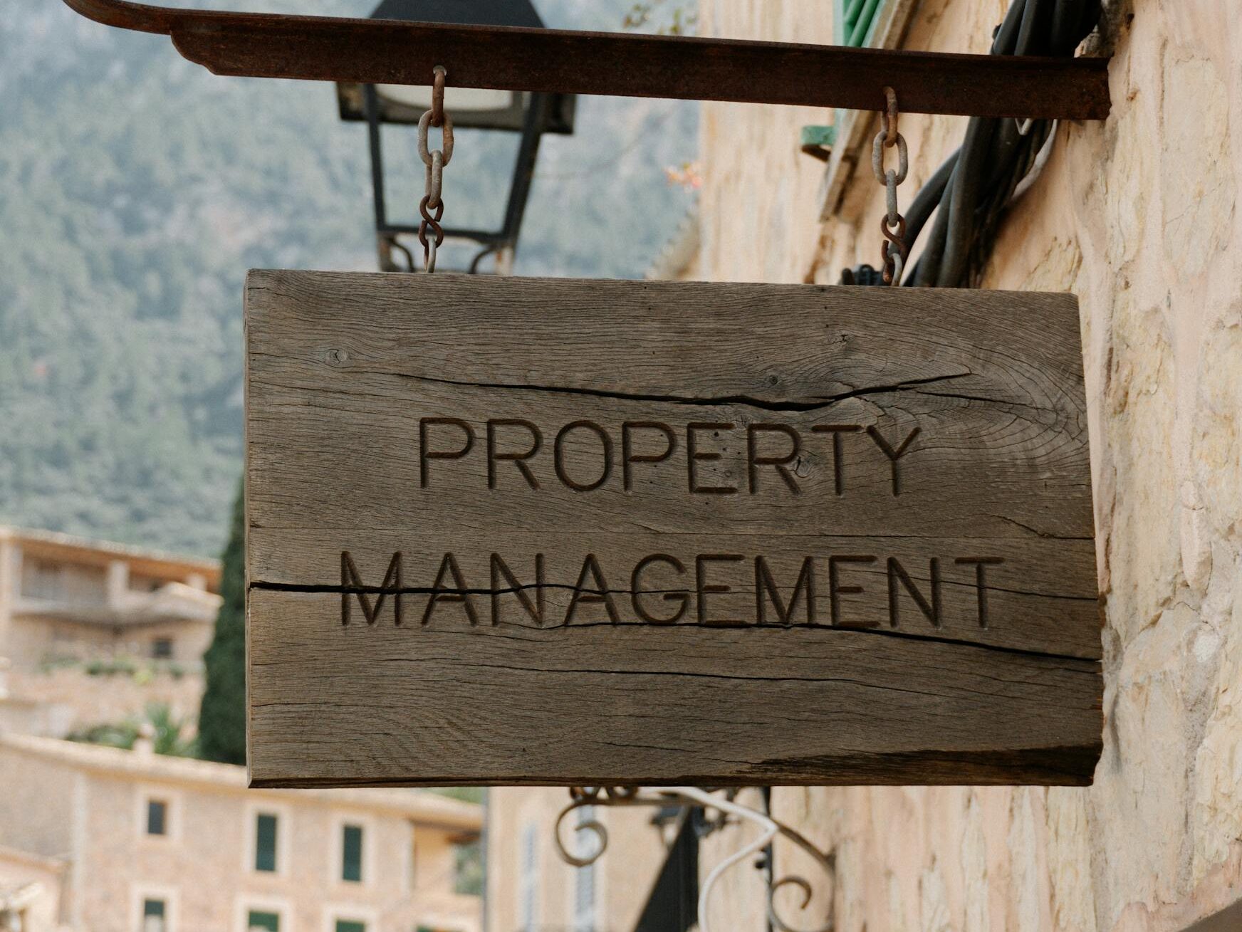 Wooden property management sign in a picturesque European village, featuring charming architecture.